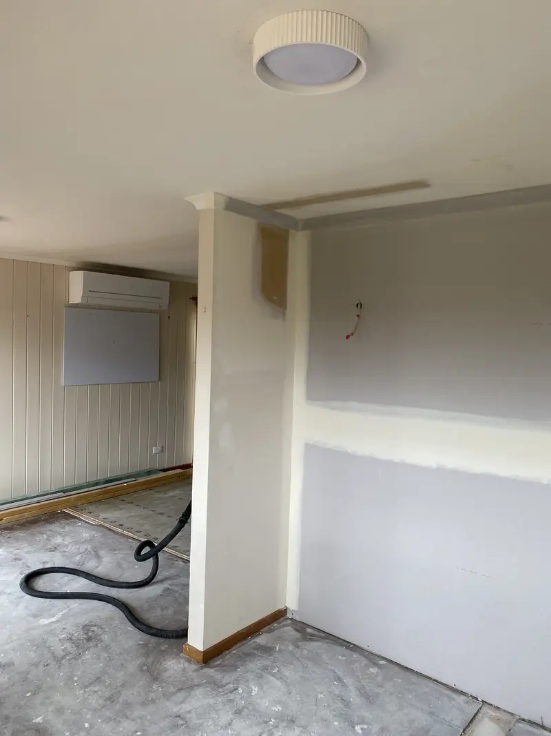 Plasterer applying skim coat over existing plaster during renovation in Seymour